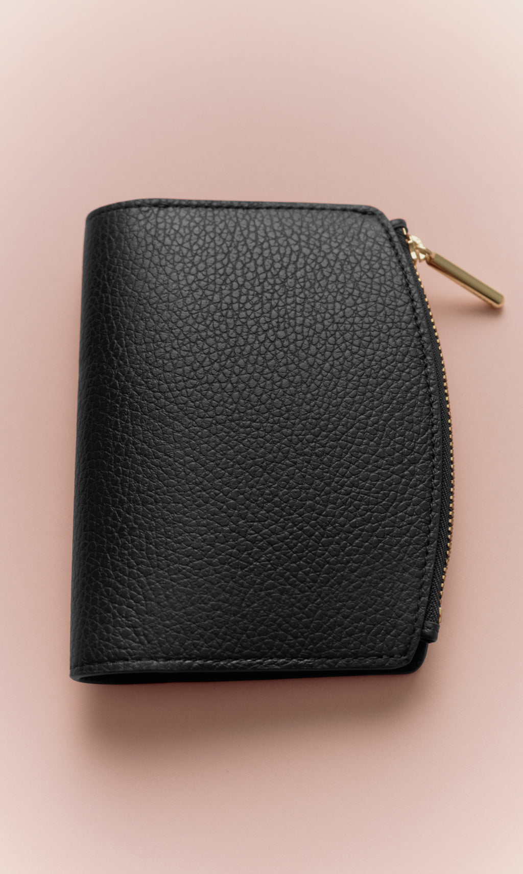 Small textured leather wallet with zippered edge on plain background