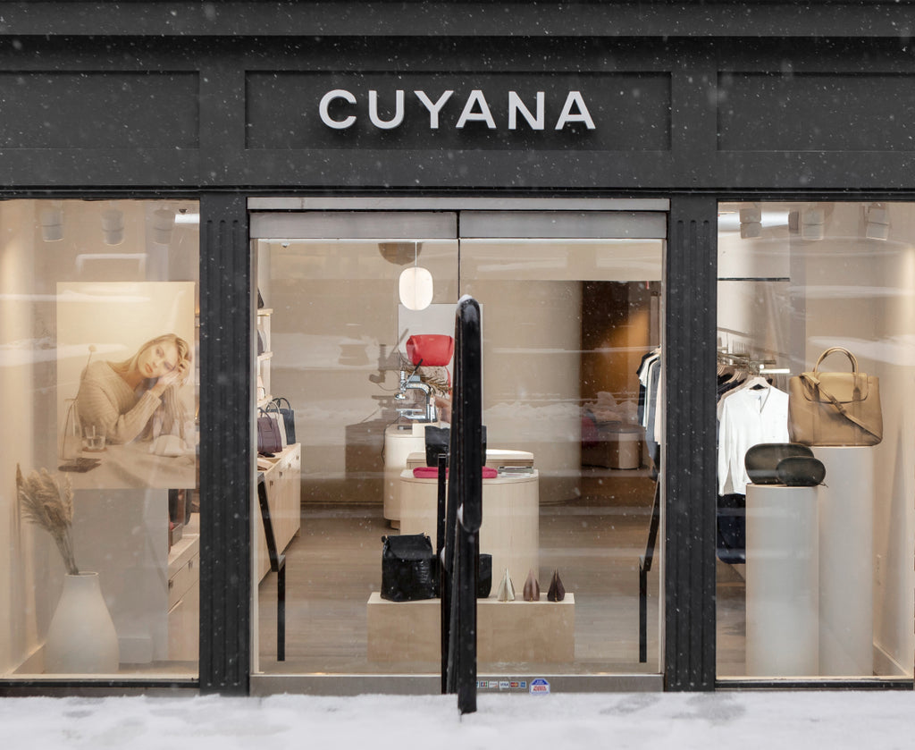 Storefront with large windows, door, and clothing displays inside.