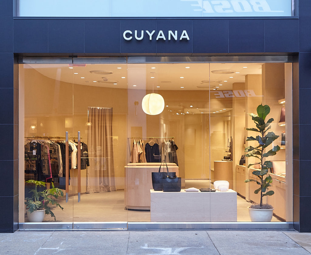Storefront with clothes, shelves, and plants visible inside.