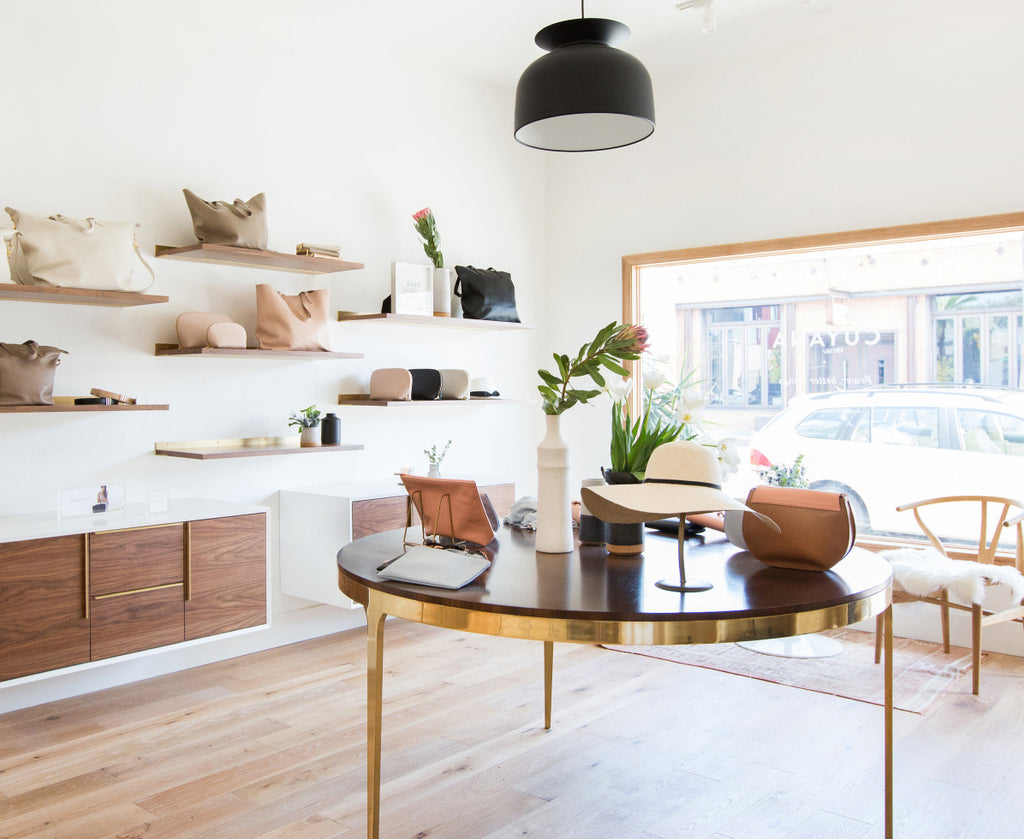 Store interior with shelves and table displaying bags and decor items.