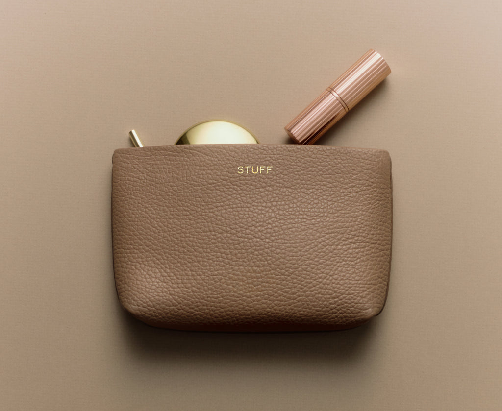 Pouch with a compact and a lipstick partially inside.