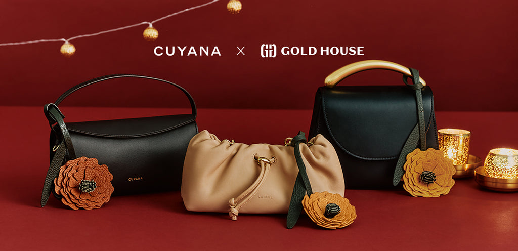 Three handbags with decorative flower charms displayed on a red surface with candles nearby.