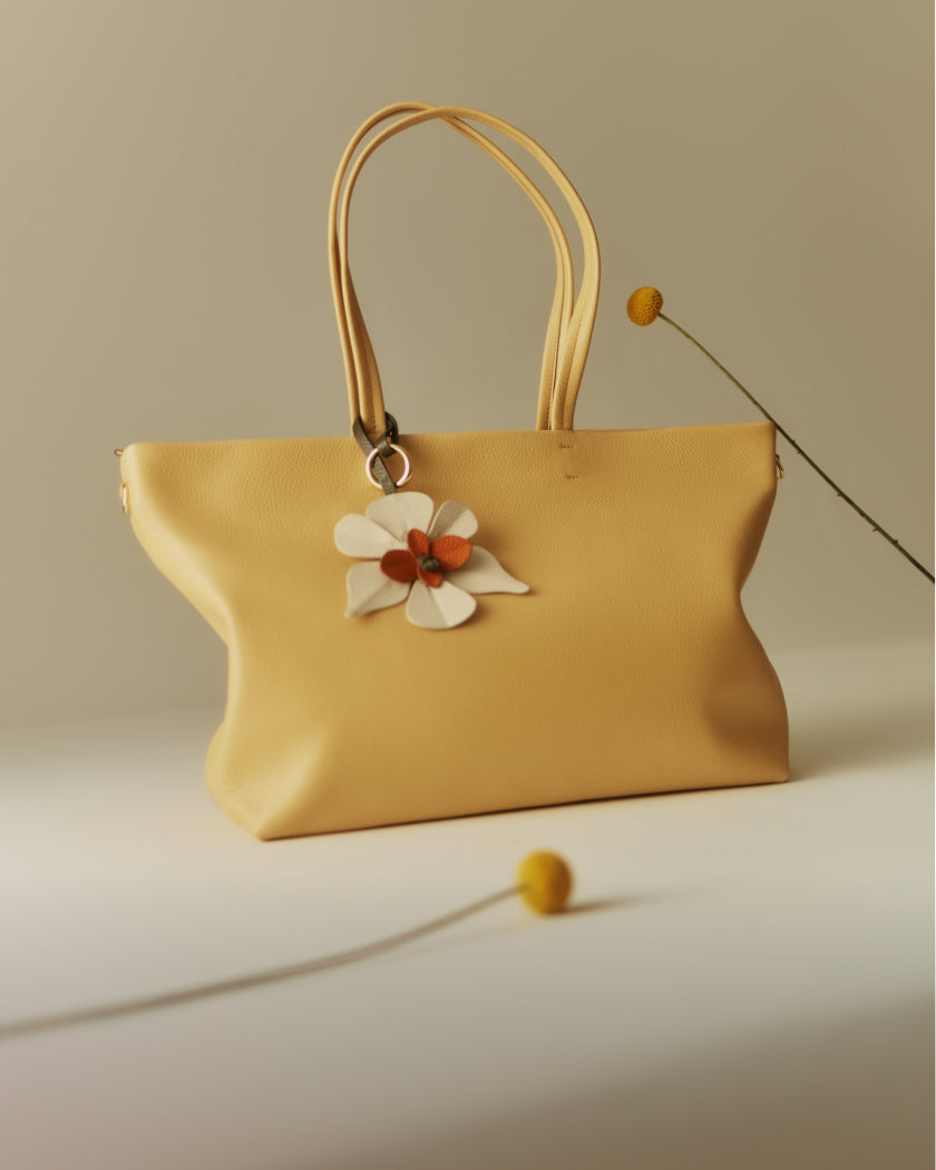 Handbag with a flower charm on a surface, with abstract flower decor.