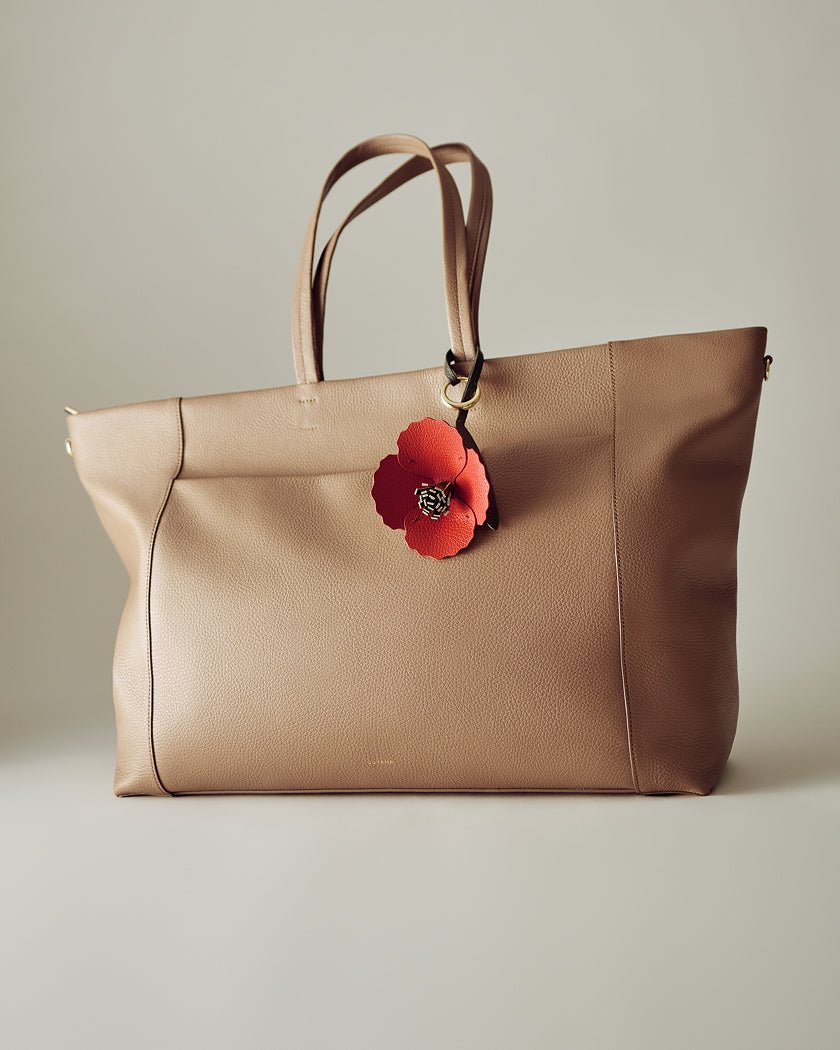 Large tote bag with floral charm on handle.