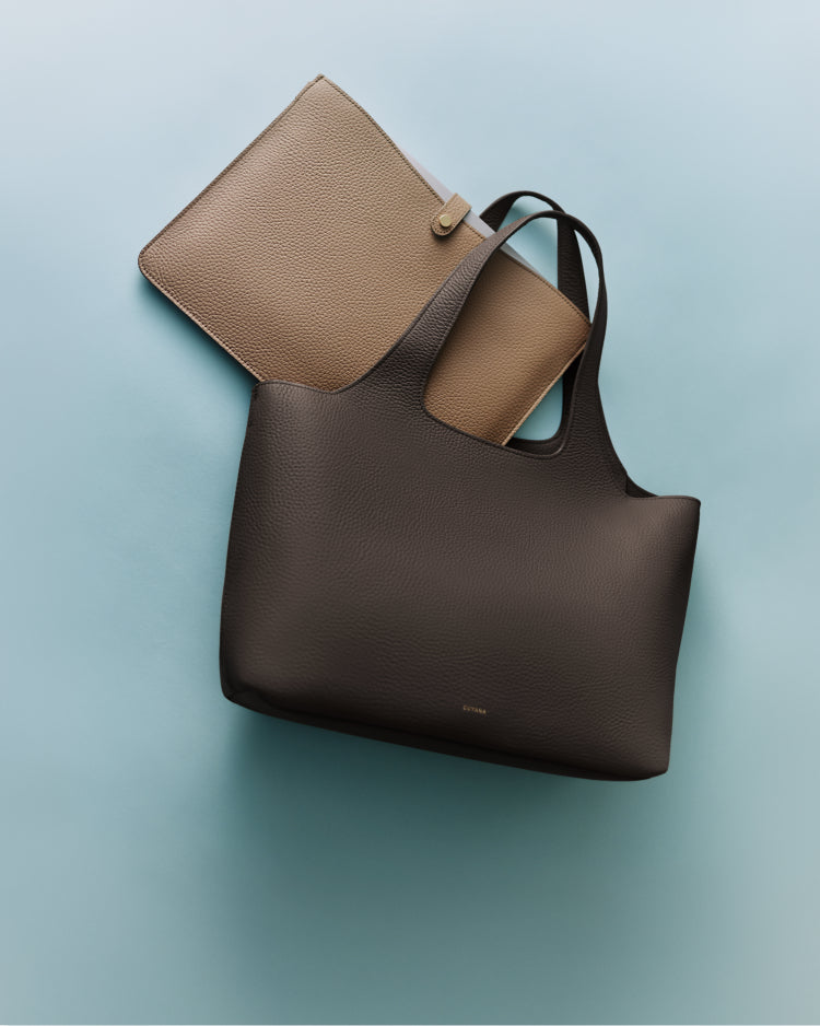 Two handbags, one inside the other, on a smooth surface.