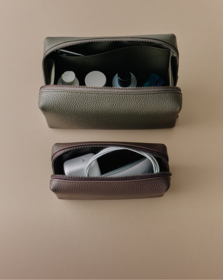 Two toiletry bags with various items inside on a flat surface.