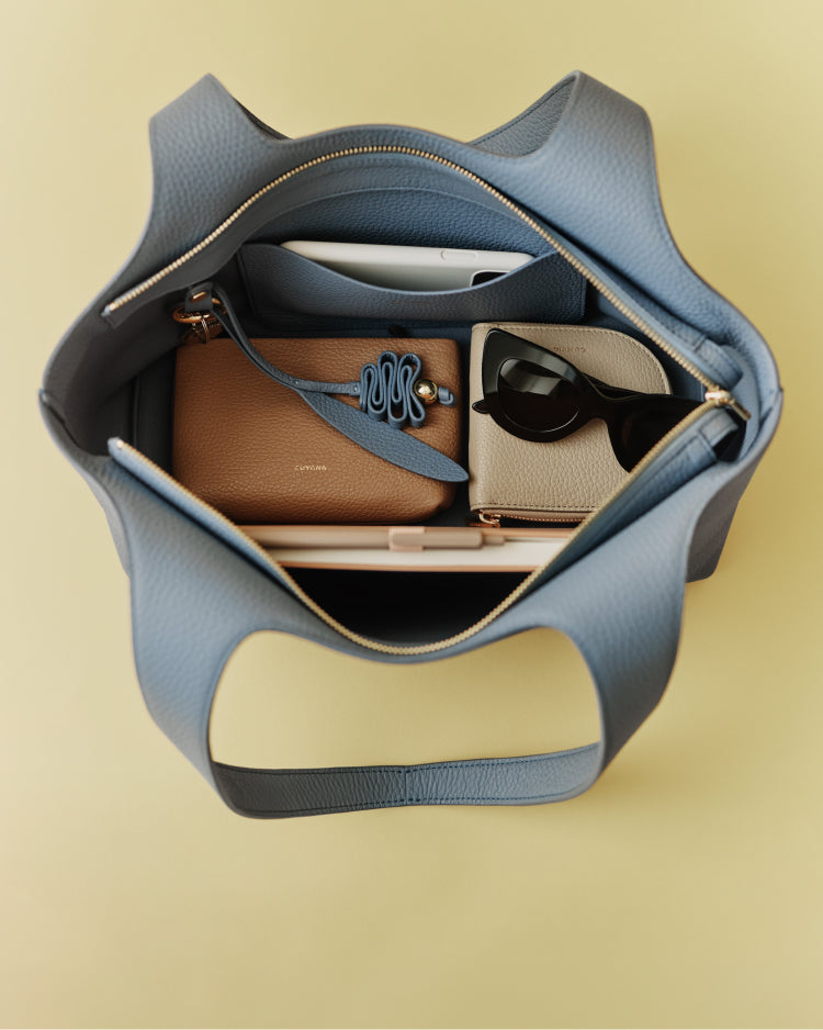 Open handbag with sunglasses, books, and small wallet inside.