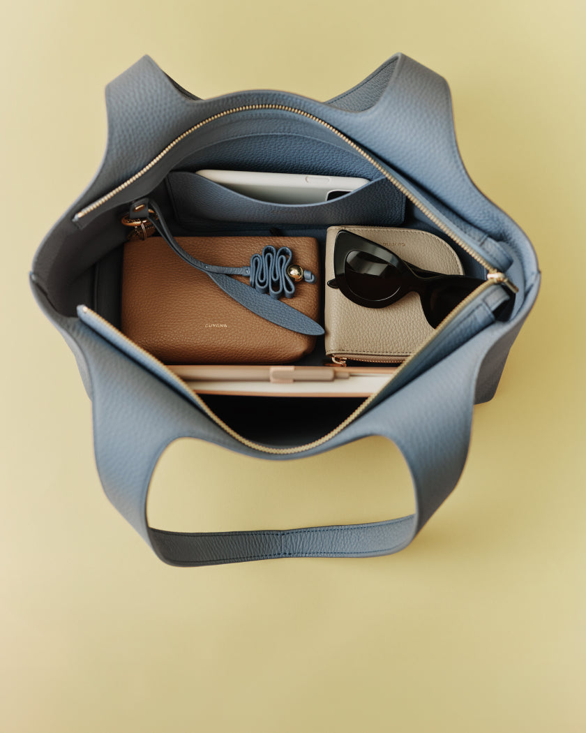 Open handbag with wallet, sunglasses, and a phone inside.
