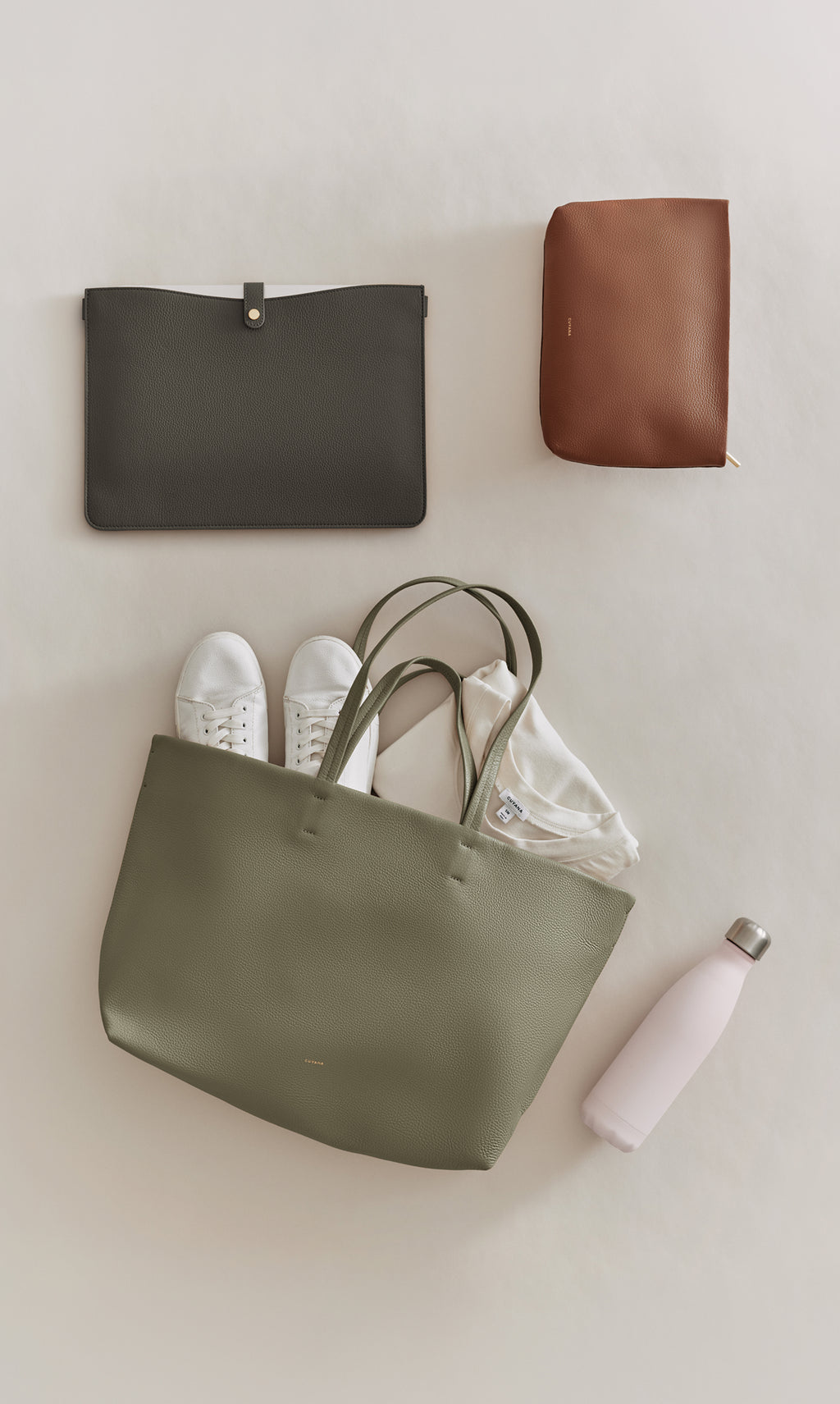 Tote bag with sneakers, pouch, clutch, and water bottle arranged on surface.