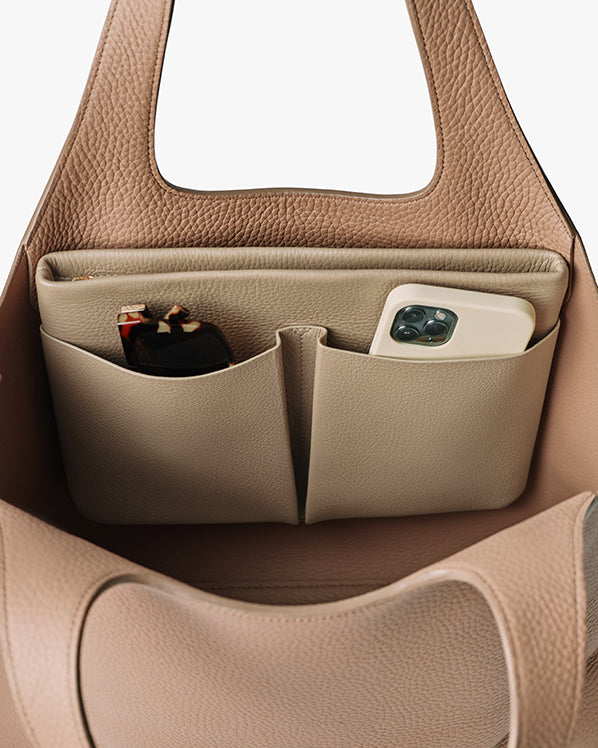 Open handbag with two inside pockets holding sunglasses and a smartphone