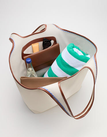 Open tote bag with towel, bottle, and toiletries inside.