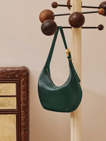 Shoulder bag hanging on a stand with decorative balls.