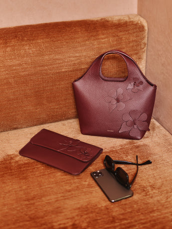 Handbag, clutch, phone, and sunglasses on a couch.