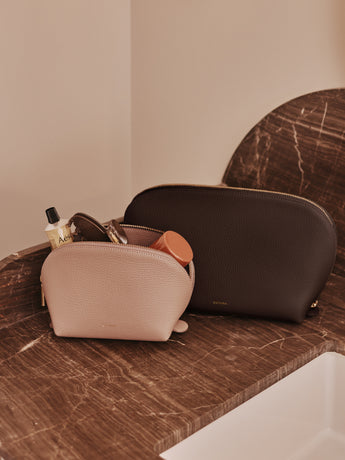 Two toiletry bags on a marble counter, one with items inside