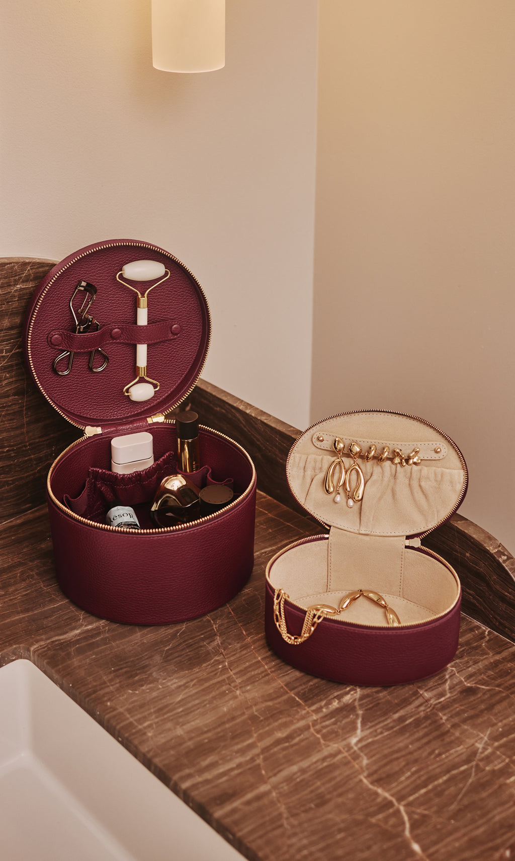 Two open round cases with beauty items on a countertop.