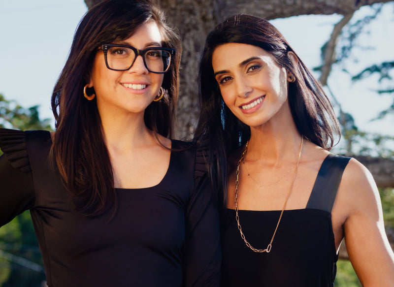 Two people standing in front of a tree, both smiling at the camera.