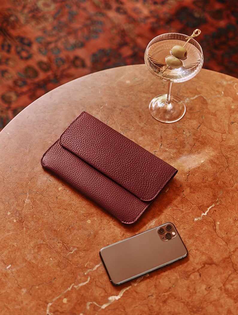 Clutch, smartphone, and cocktail on a round table.