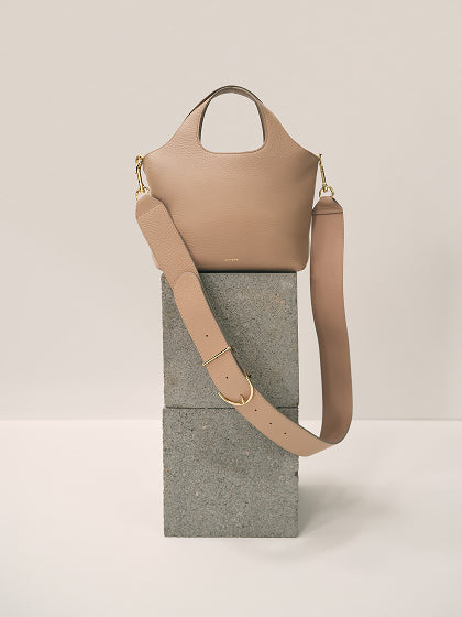 Handbag with wide strap displayed on stone blocks