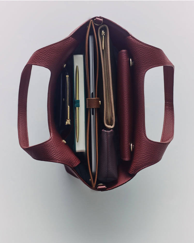 Top view of an open tote bag filled with notebooks and pouches.
