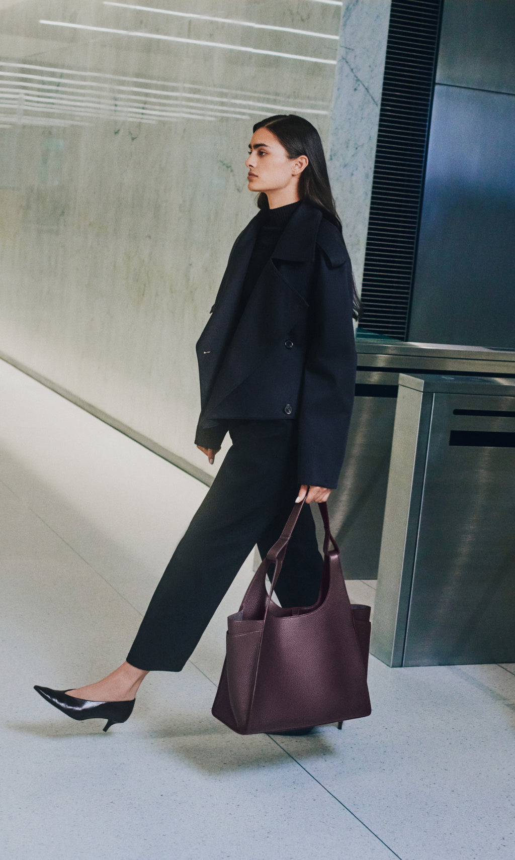 Person walking indoors carrying a large tote bag
