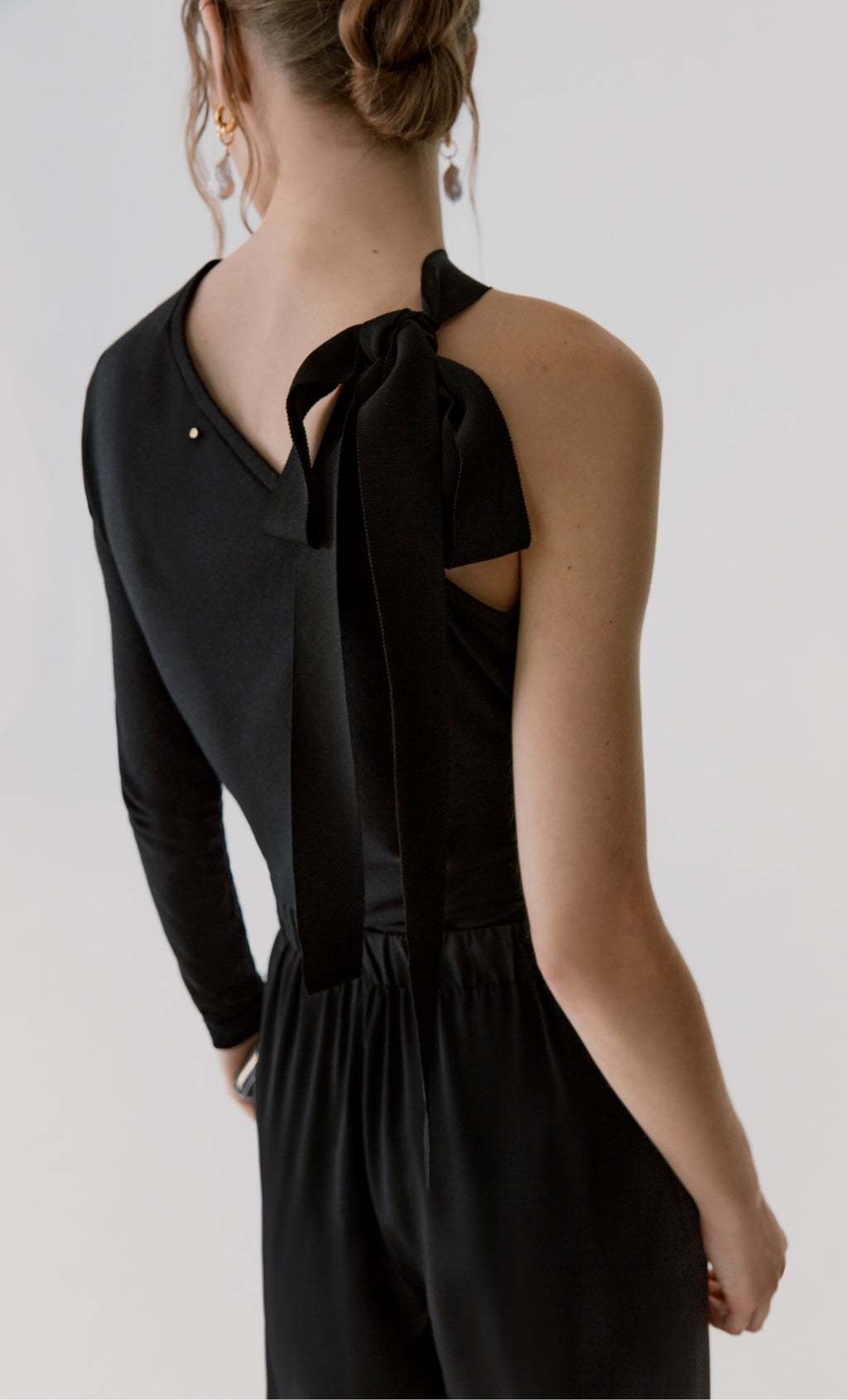 Person in one-sleeve top with bow detail on shoulder.