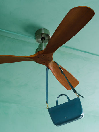 Ceiling fan with a handbag hanging from one of its blades.