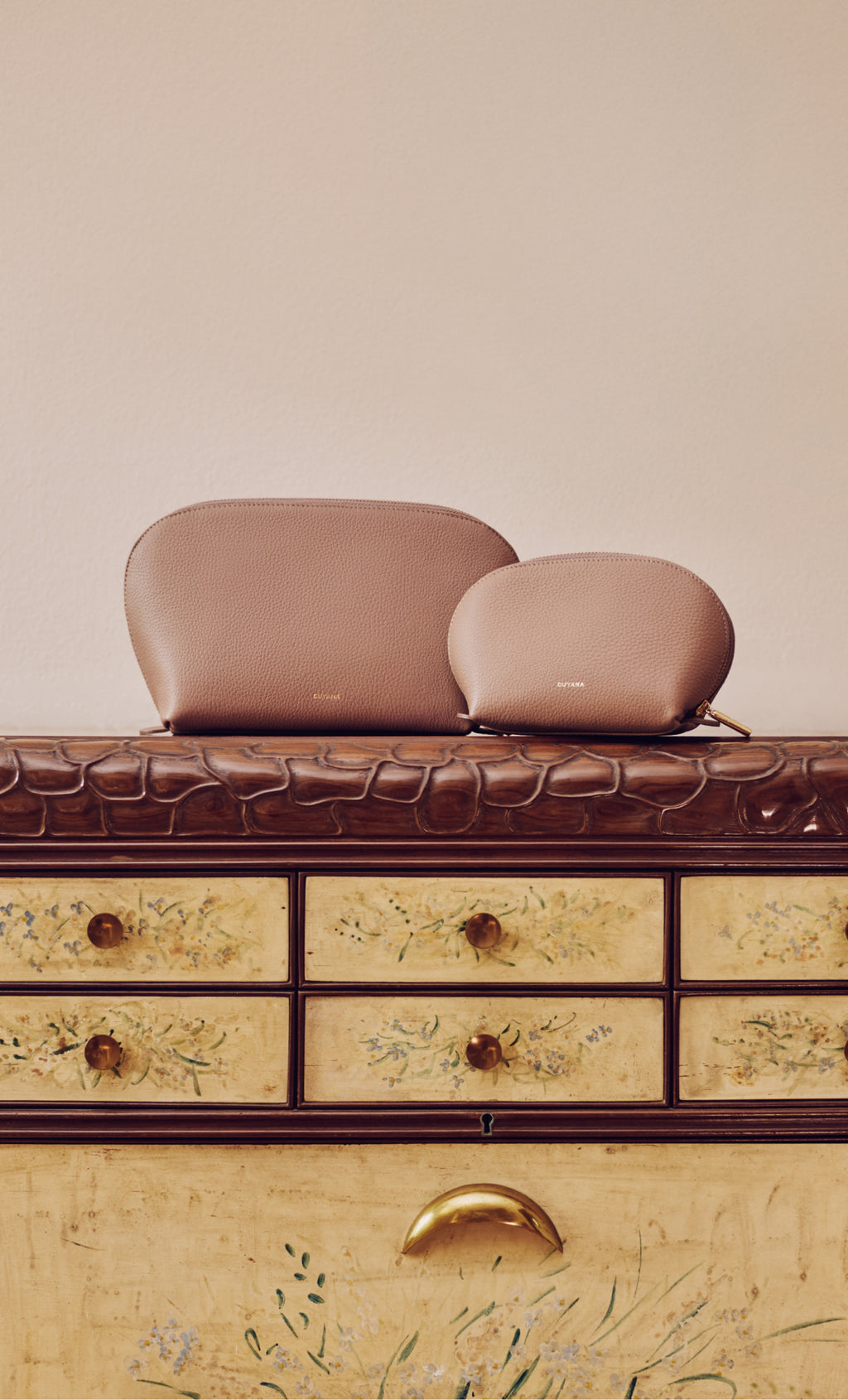 Two zippered pouches on a dresser with croc-embossed leather accents.