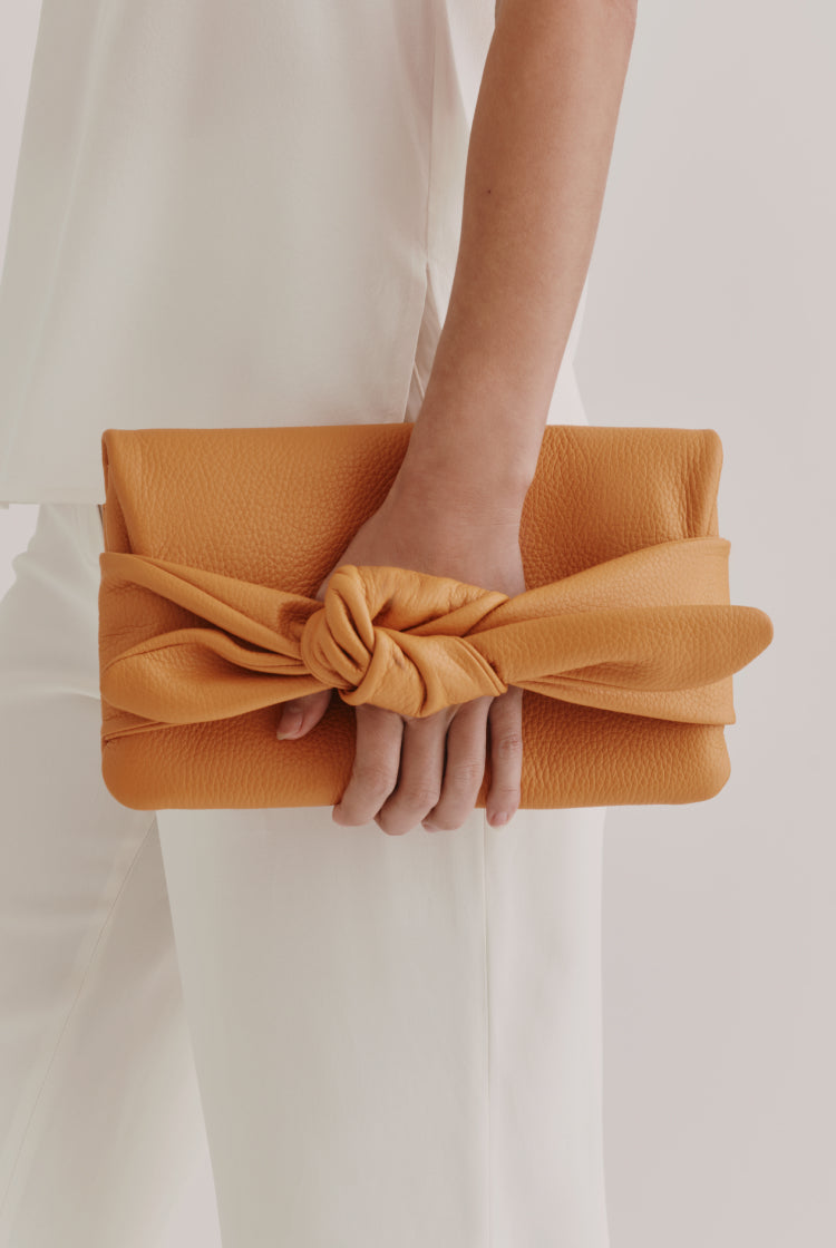 Person holding a clutch with a knot design