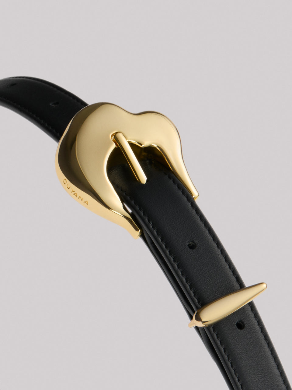 A belt with a gold heart-shaped buckle and a loop.