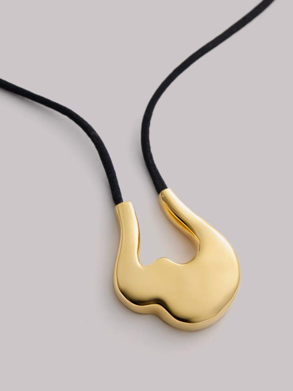 Gold pendant on black cord necklace