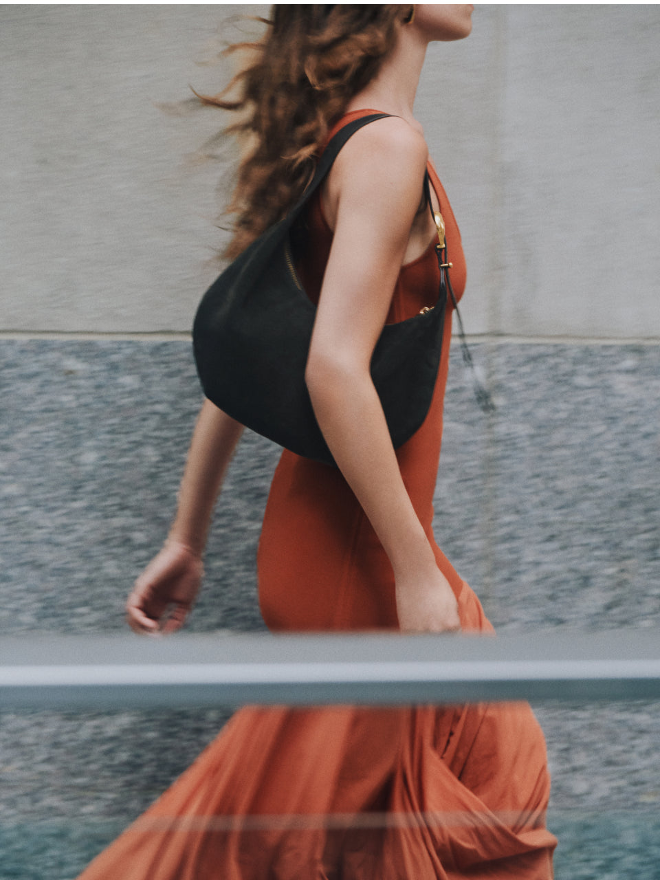 Person walking with shoulder bag and flowing dress