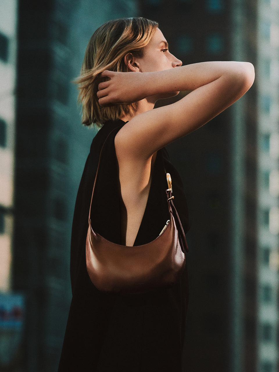 Person in city holding shoulder bag, looking up
