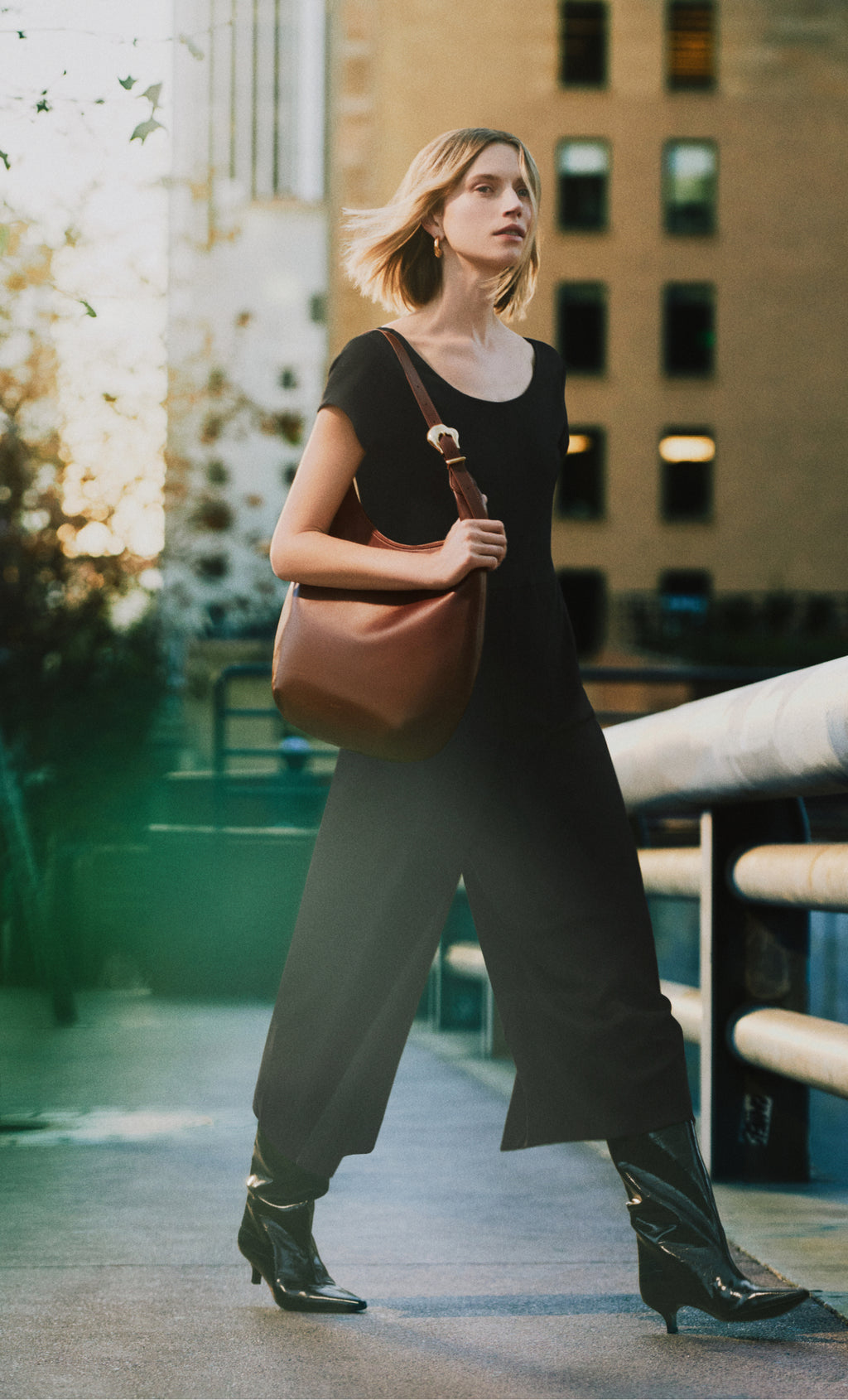 Person walking on a city street, holding a shoulder bag.