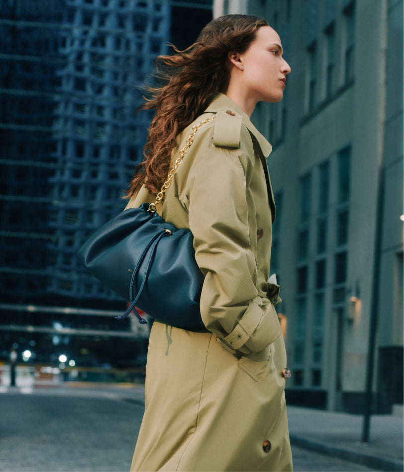 Person walking in city wearing a coat, holding a handbag over the shoulder.
