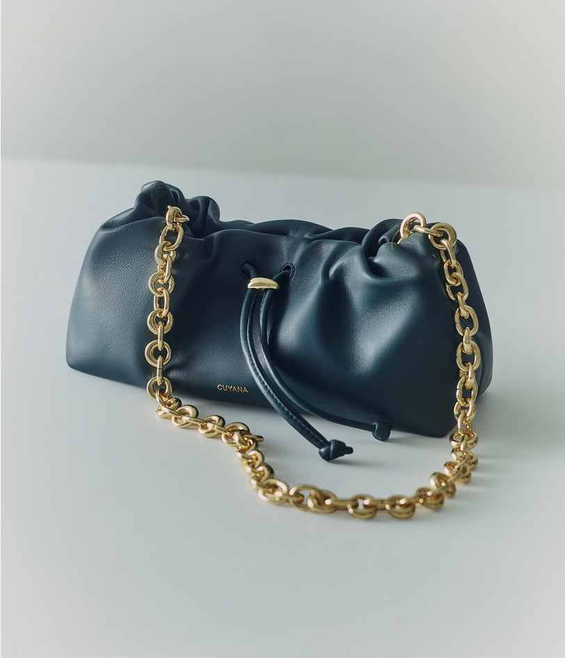 Bag with chain strap and drawstring on flat surface