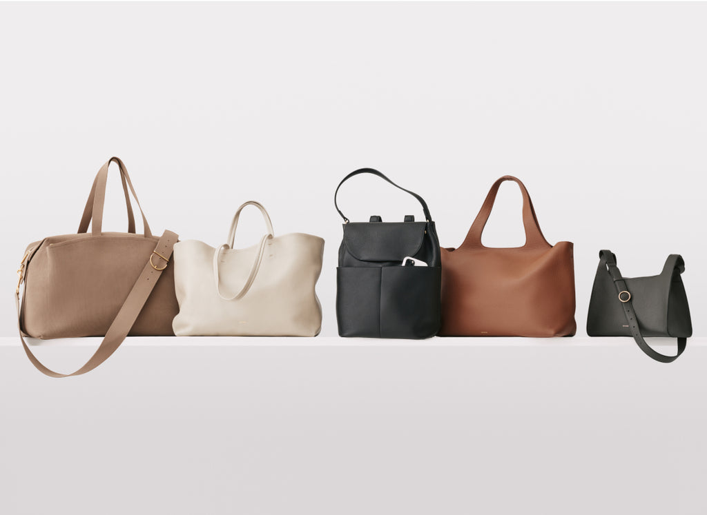 Five assorted handbags in a row against a plain background.