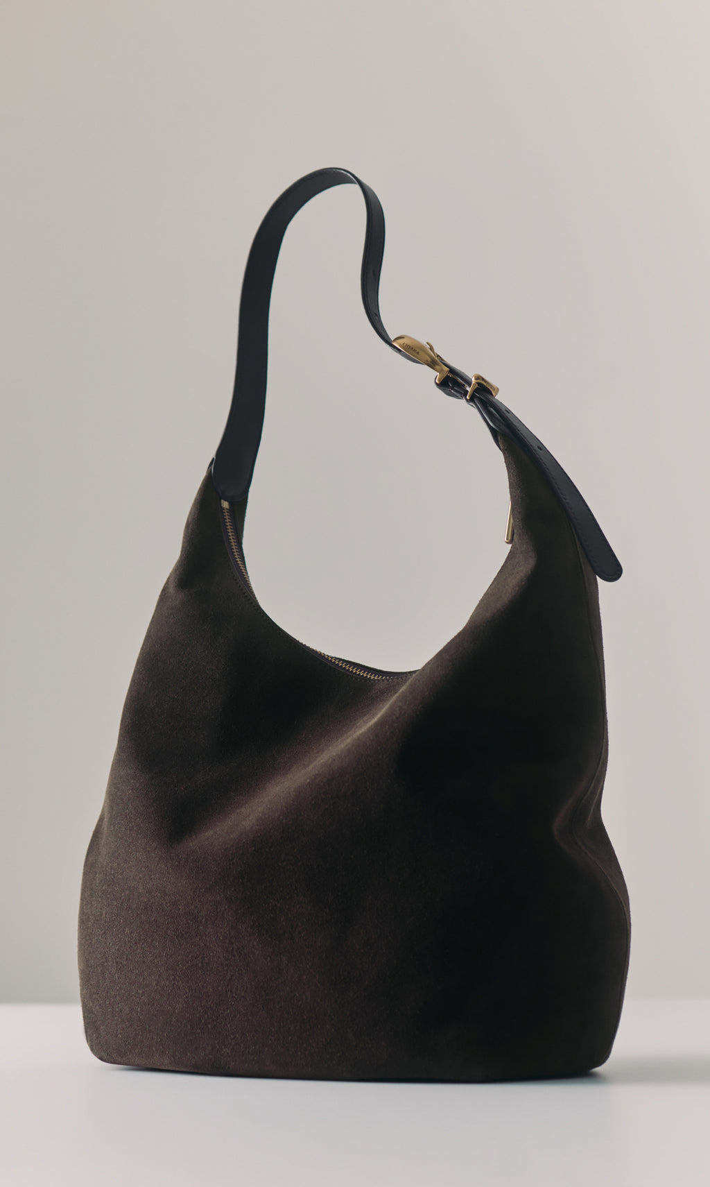 Slouchy handbag with a strap on a plain surface
