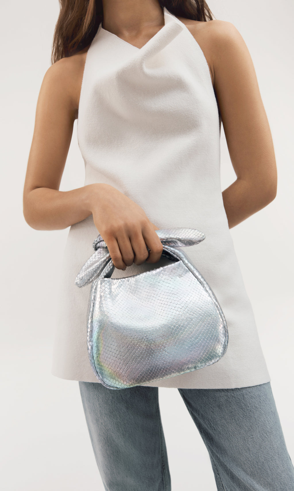 Person in sleeveless top holding a small metallic bag.