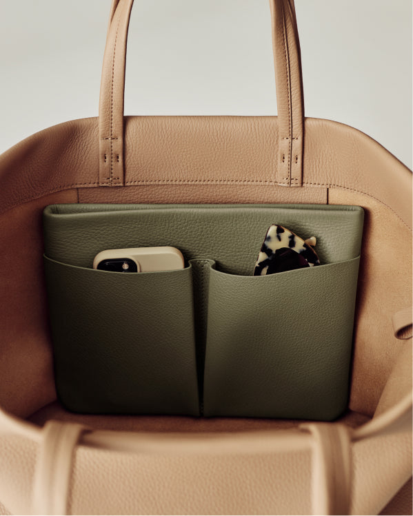 Open handbag with phone and patterned item in pockets.