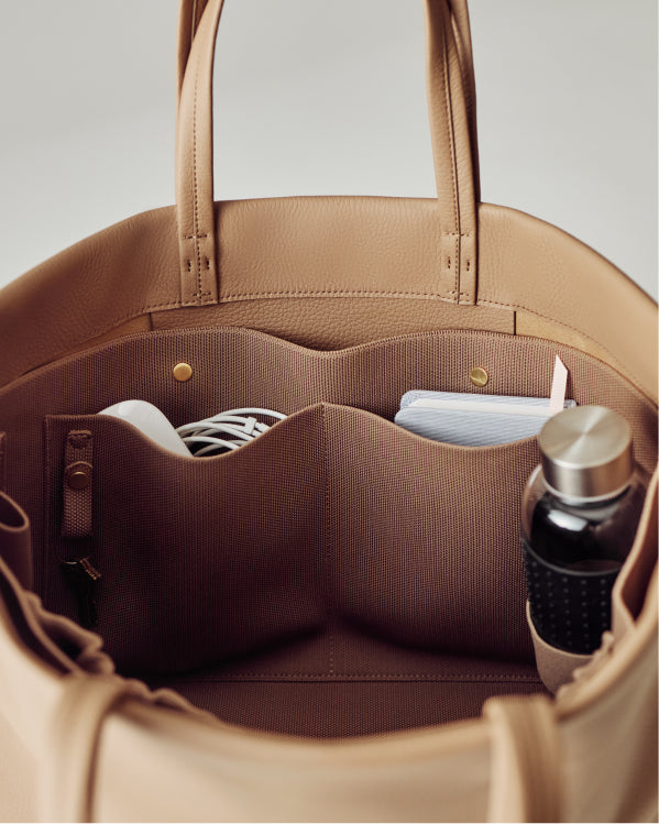 Open bag with pockets showing a book, water bottle, and coiled cable inside.