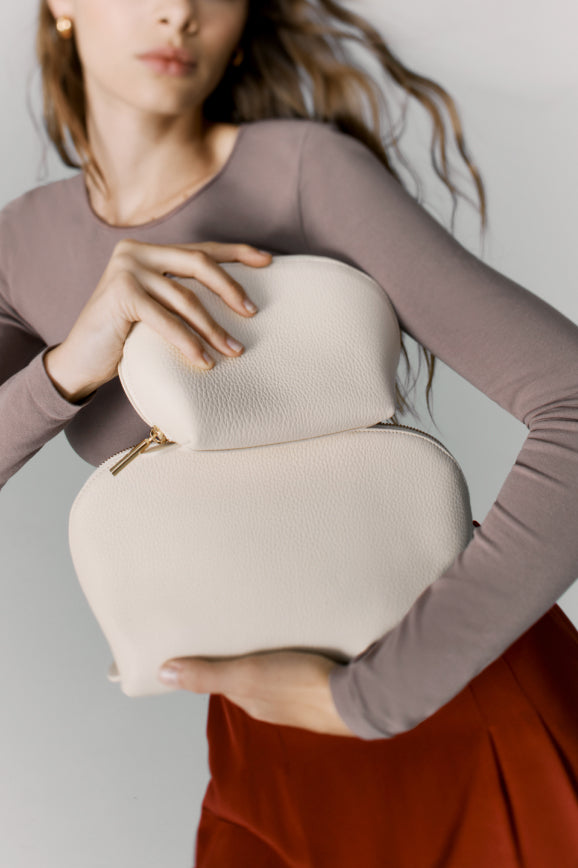 Person holding two matching textured pouches against their chest