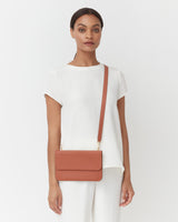 Woman standing with a shoulder bag.