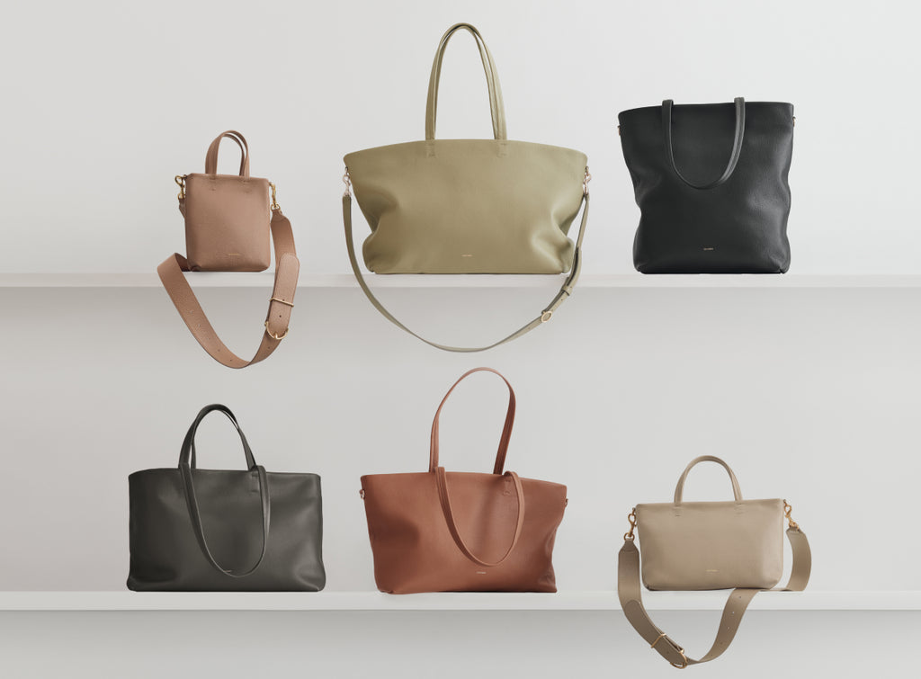 Six handbags displayed on two shelves against a plain wall.