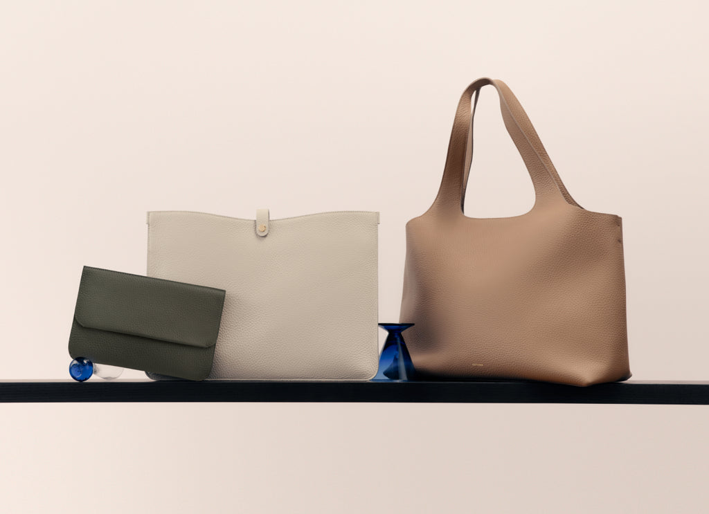 Three bags on a shelf with a small decorative item.