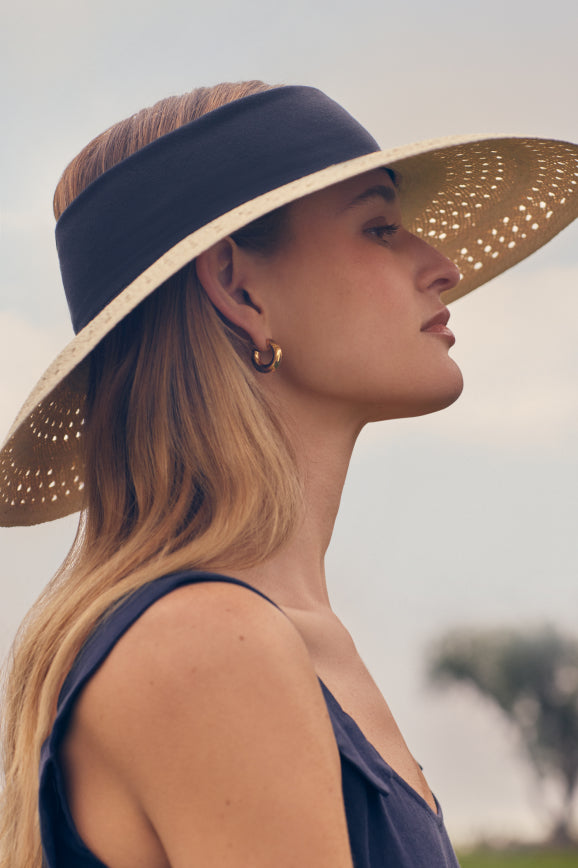 Profile view of a woman wearing a wide-brimmed hat outdoors