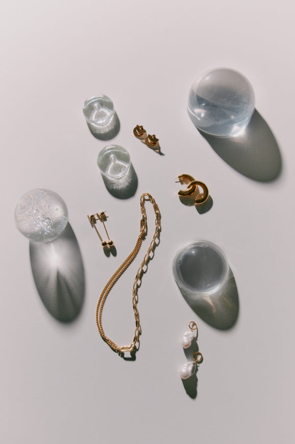 Arrangement of various jewelry pieces and glass objects on a flat surface.