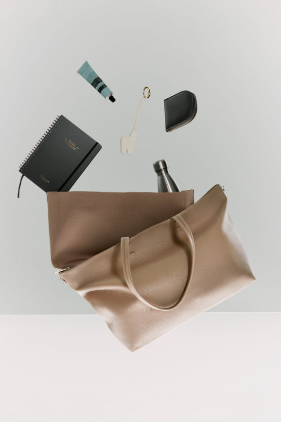 Items floating out of a tote bag against a light background.