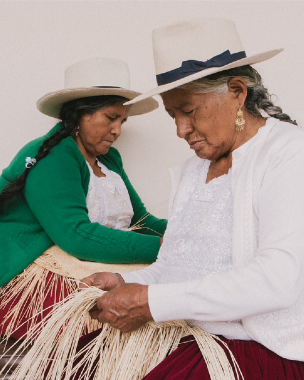 Two women in hats weaving together