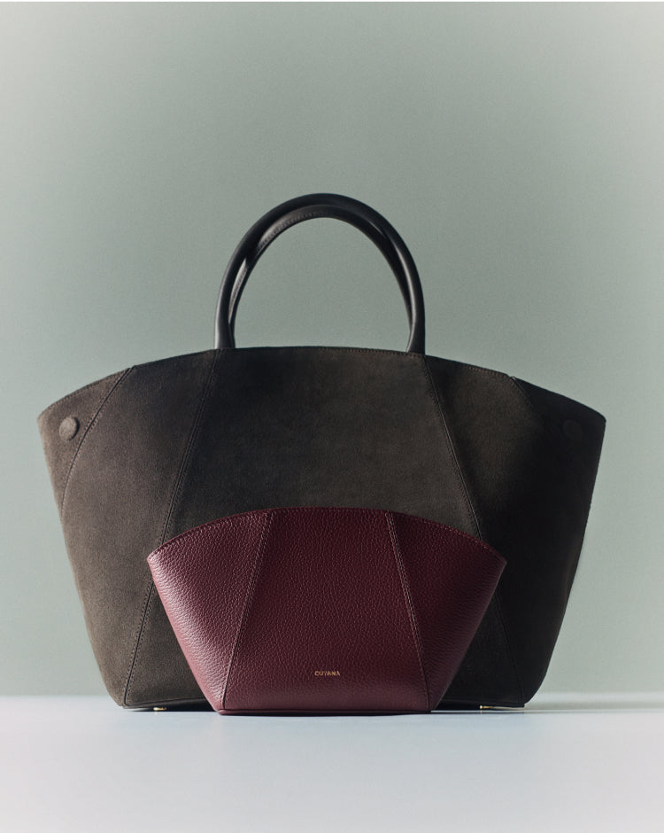 Large handbag and a small clutch in front of it on a flat surface