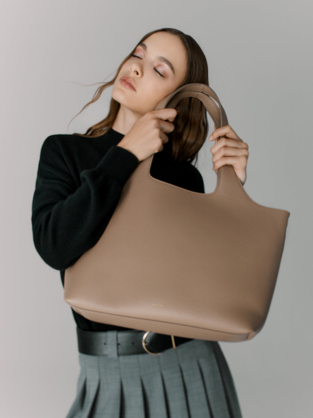 Woman holding a large handbag, looking away from the camera.